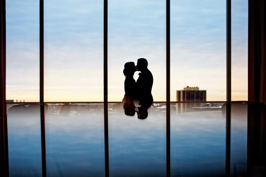 bride and groom kissing with sky reflexion