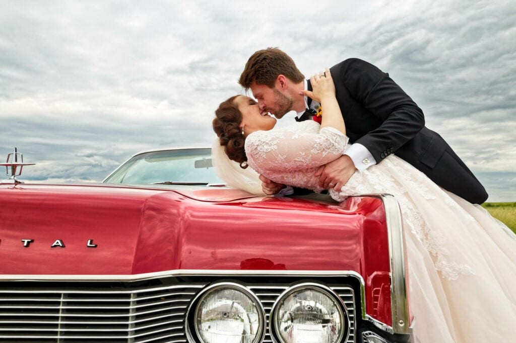 newly married couple kissing on old red american car