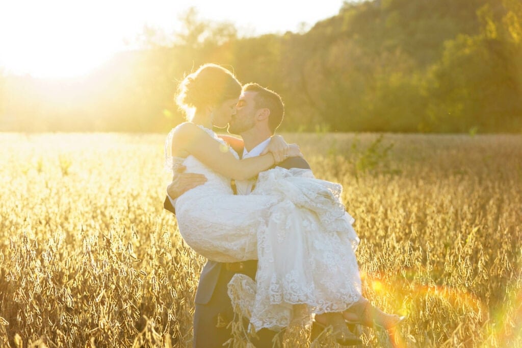 newlywed couple kissing during sunset light in a filed