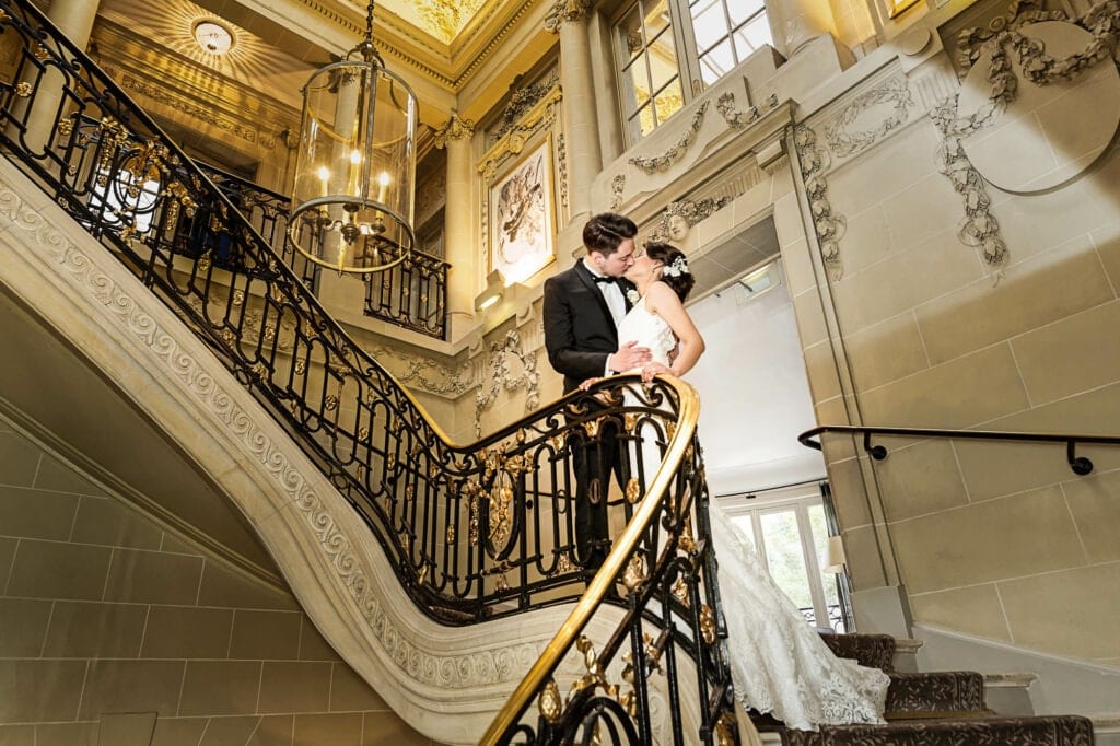 pictures of newly married couple kissing on luxurious stairs hotel