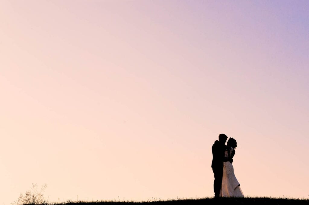 pink to blue sunset sky with bride and groom