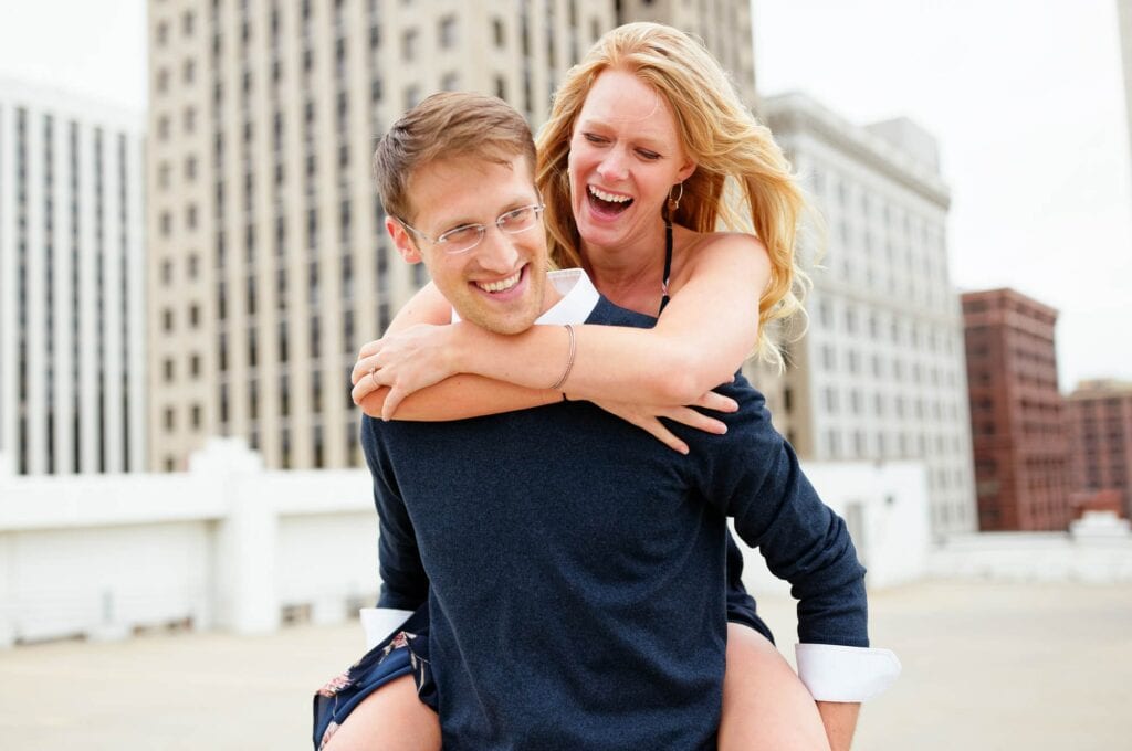 soon to be married couple on roof top playing piggyback