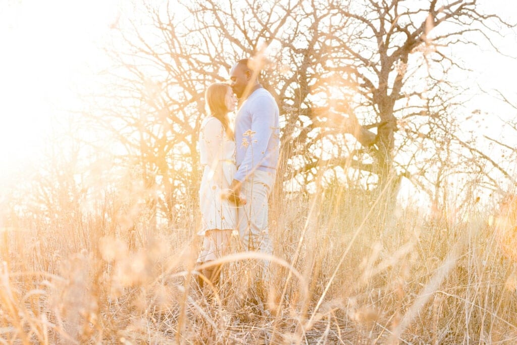 couple holding hands and kissing in meadow