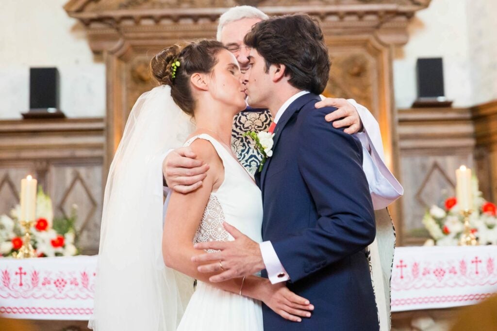 priest pushing the bride and the groom to kiss