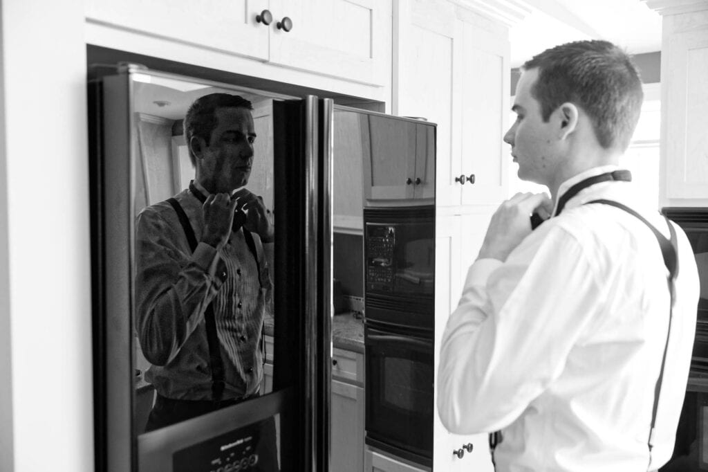 checking himself on the shiny black fridge