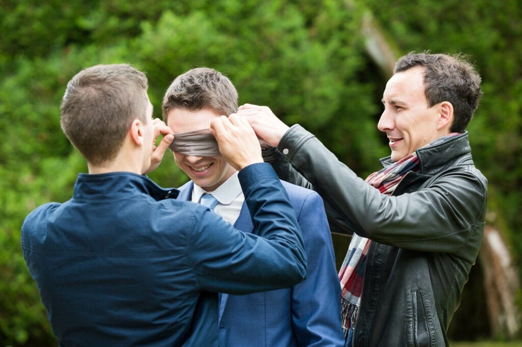 groom having his eyes covered by his groomsmen before the first look