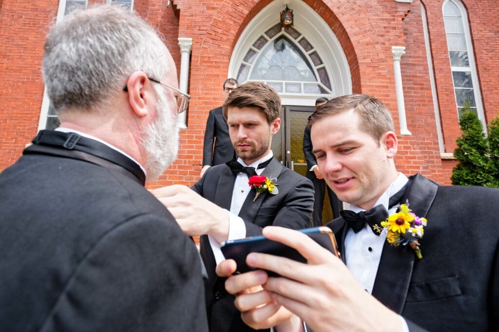 groom and his brother watching a youtube video to fix their fathers bow tie