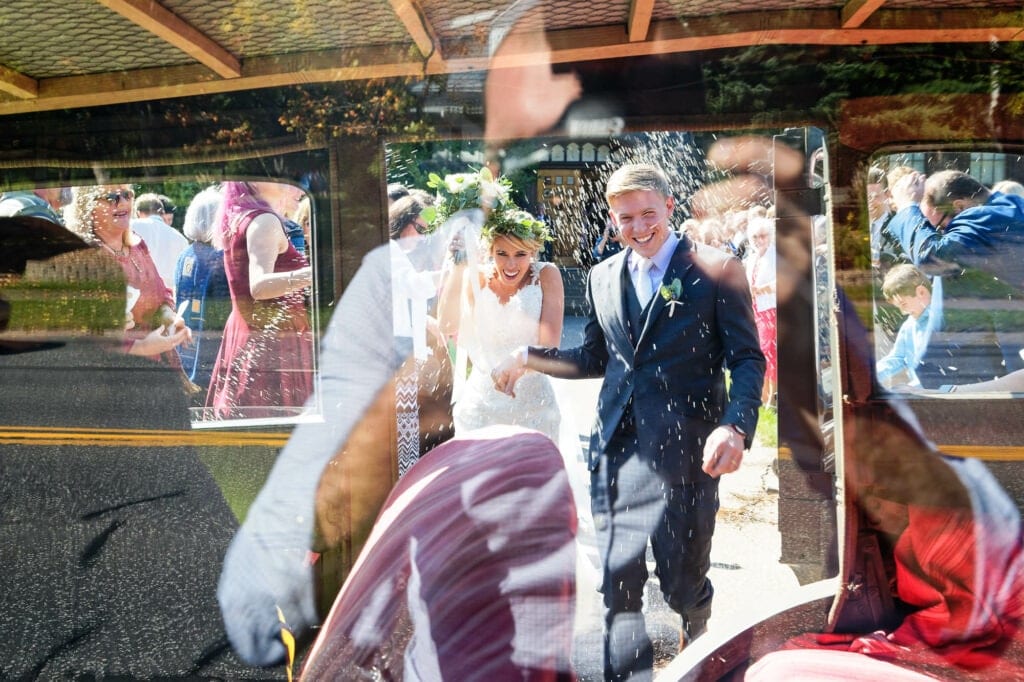 bride and groom jumping into old wedding car