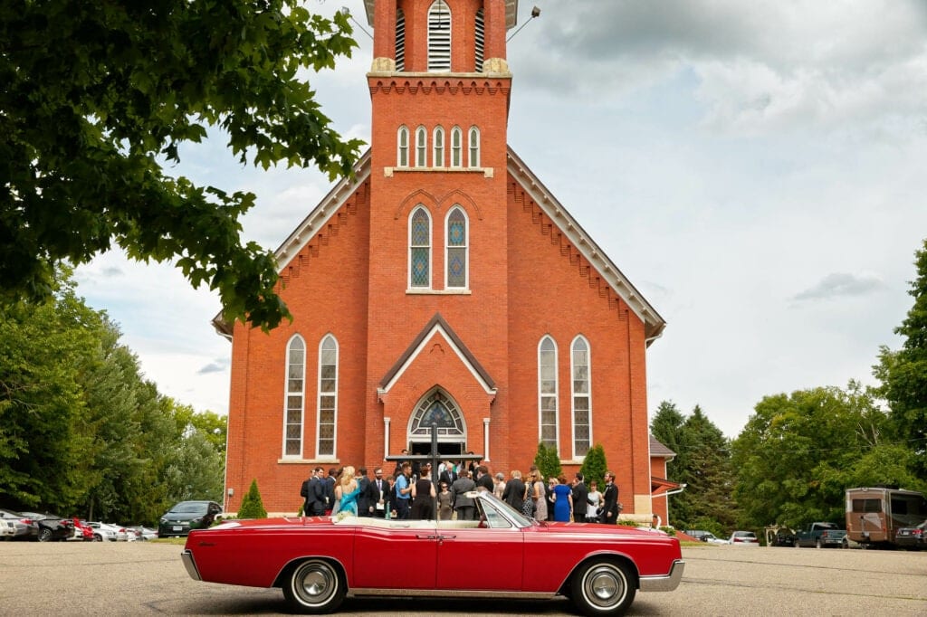 red american car in front of a red brick church