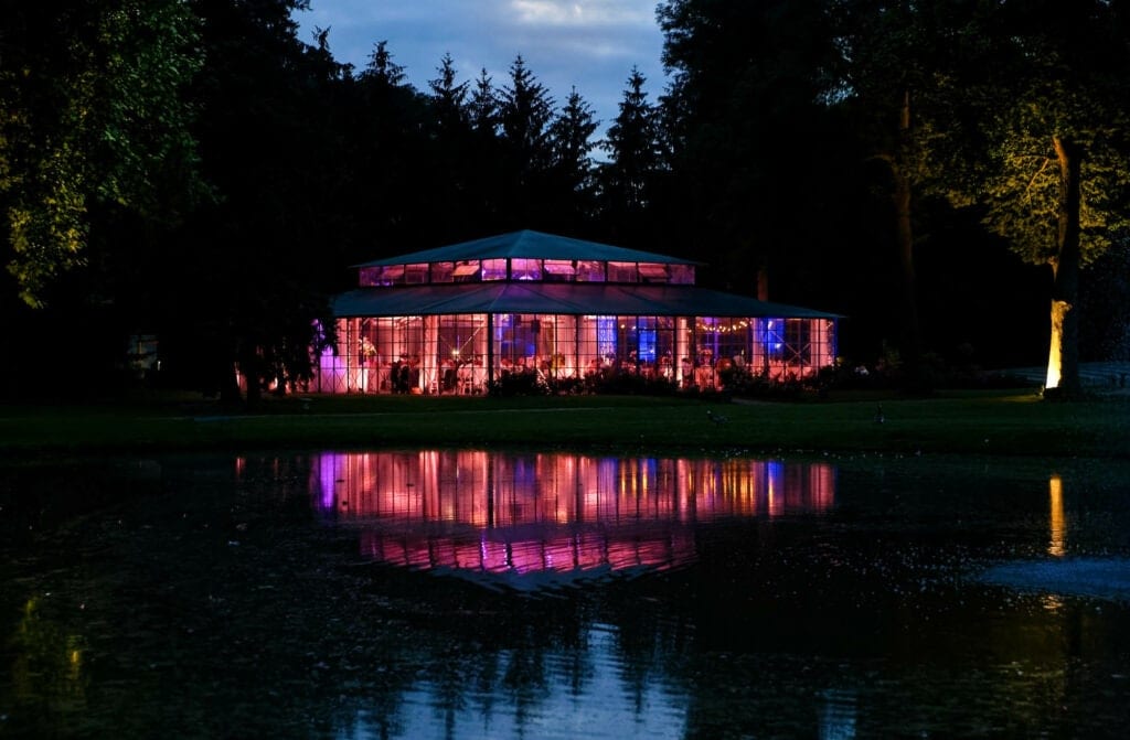 night pictures of a pink lightened green house with reflection on the water