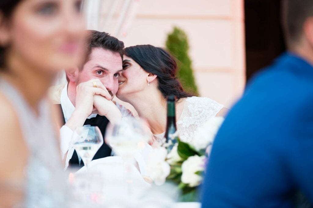 bride whispering secret to her husband during dinner