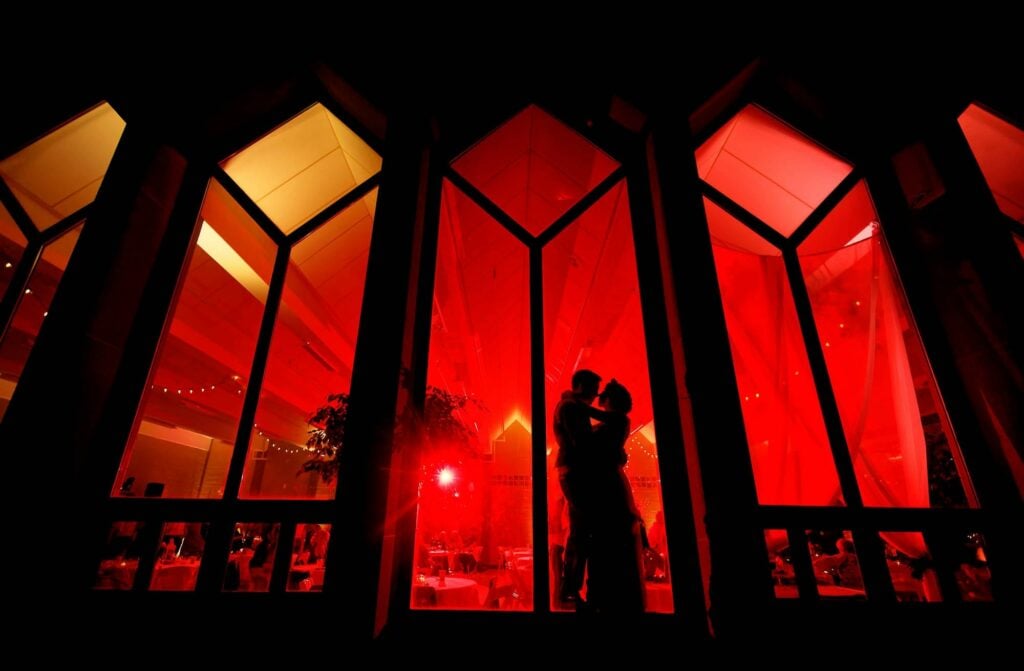 silhouette couple picture standing in front of red lightened windows