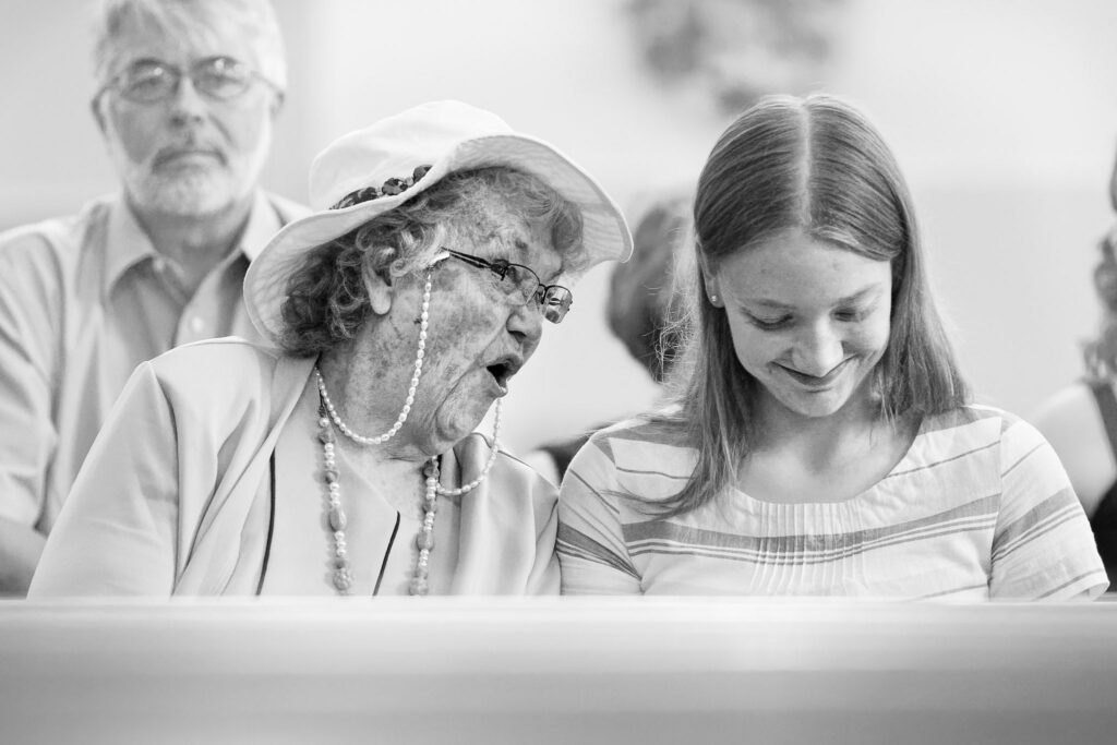 Grandmother Gossiping with Granddaughter During Wedding Ceremony