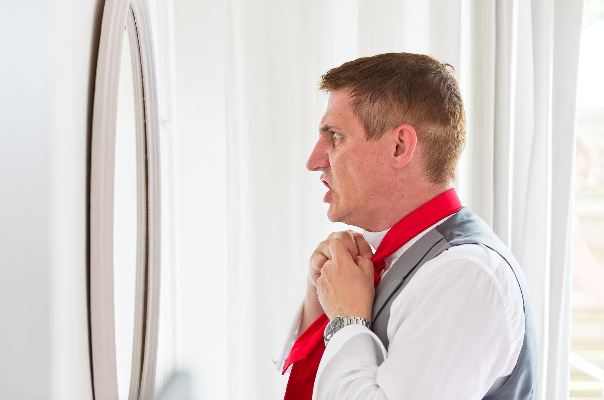 Groom Struggling with Tie During Wedding Preparations