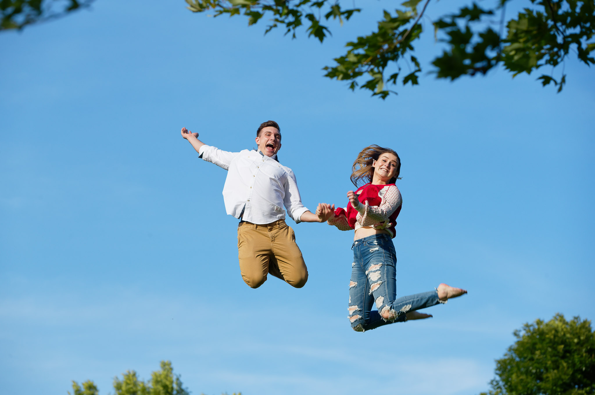 Couple Jumping Against Blue Sky - Engagement Photography