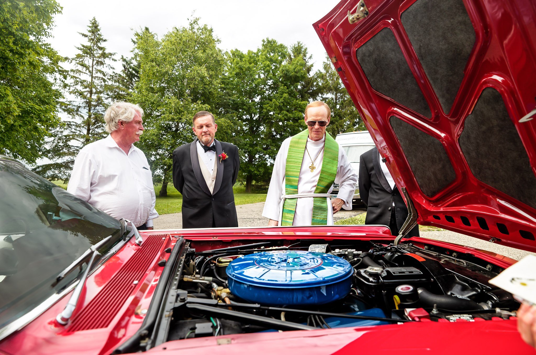 Pastor and Wedding Guests Admiring Classic Car Engine