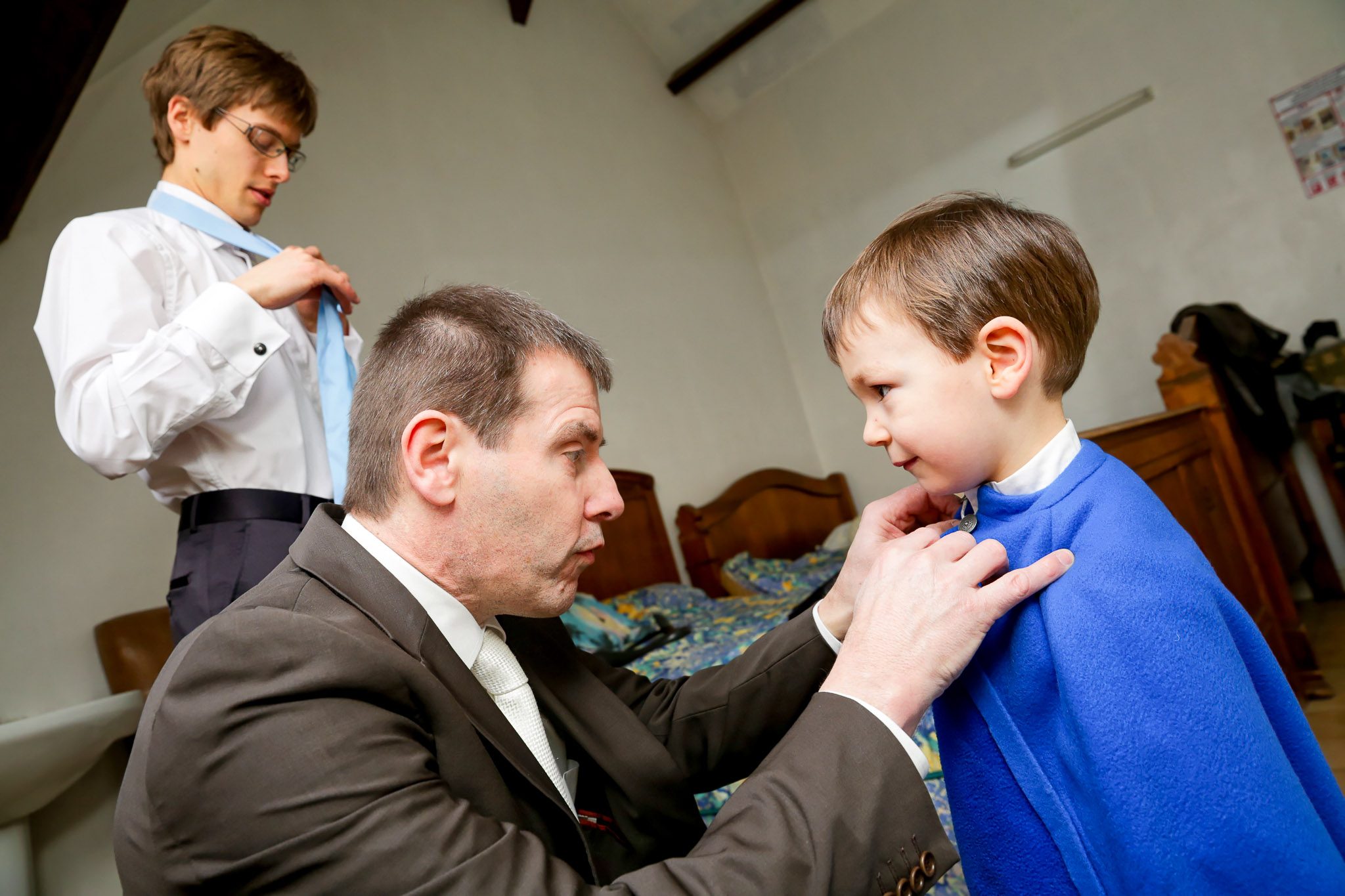 Father of Groom Helping Nephew with Cap During Wedding Prep